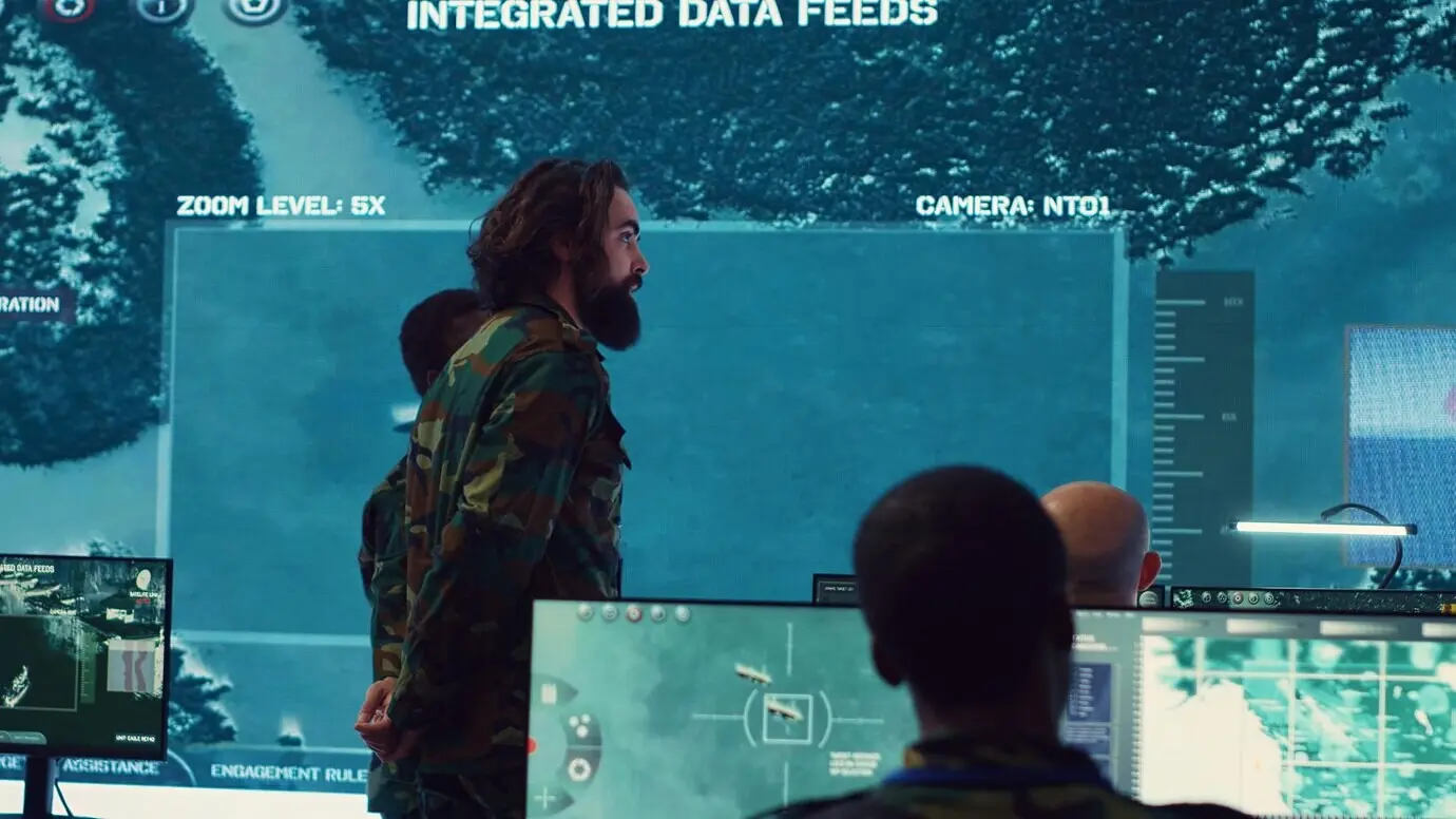 Im Generalhauptquartier unterhalten sich militärische Überwachungsoffiziere neben einem großen Bildschirm.